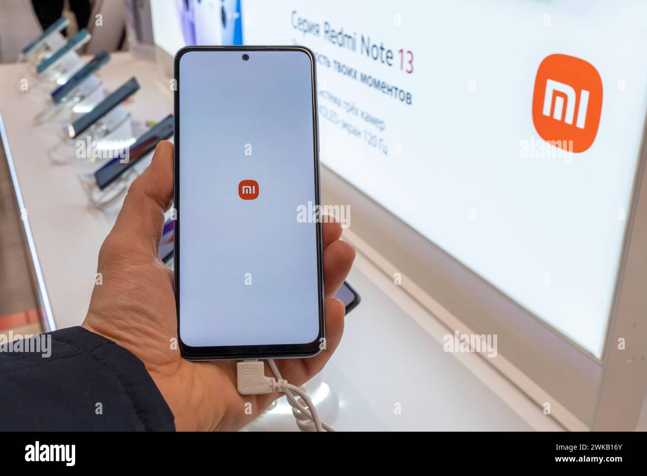 Smartphone Xiaomi avec logo sur l'écran en main. Client choisissant smartphone dans les téléphones mobiles Xiaomi magasin. Minsk, Biélorussie - 19 février 2024 Banque D'Images