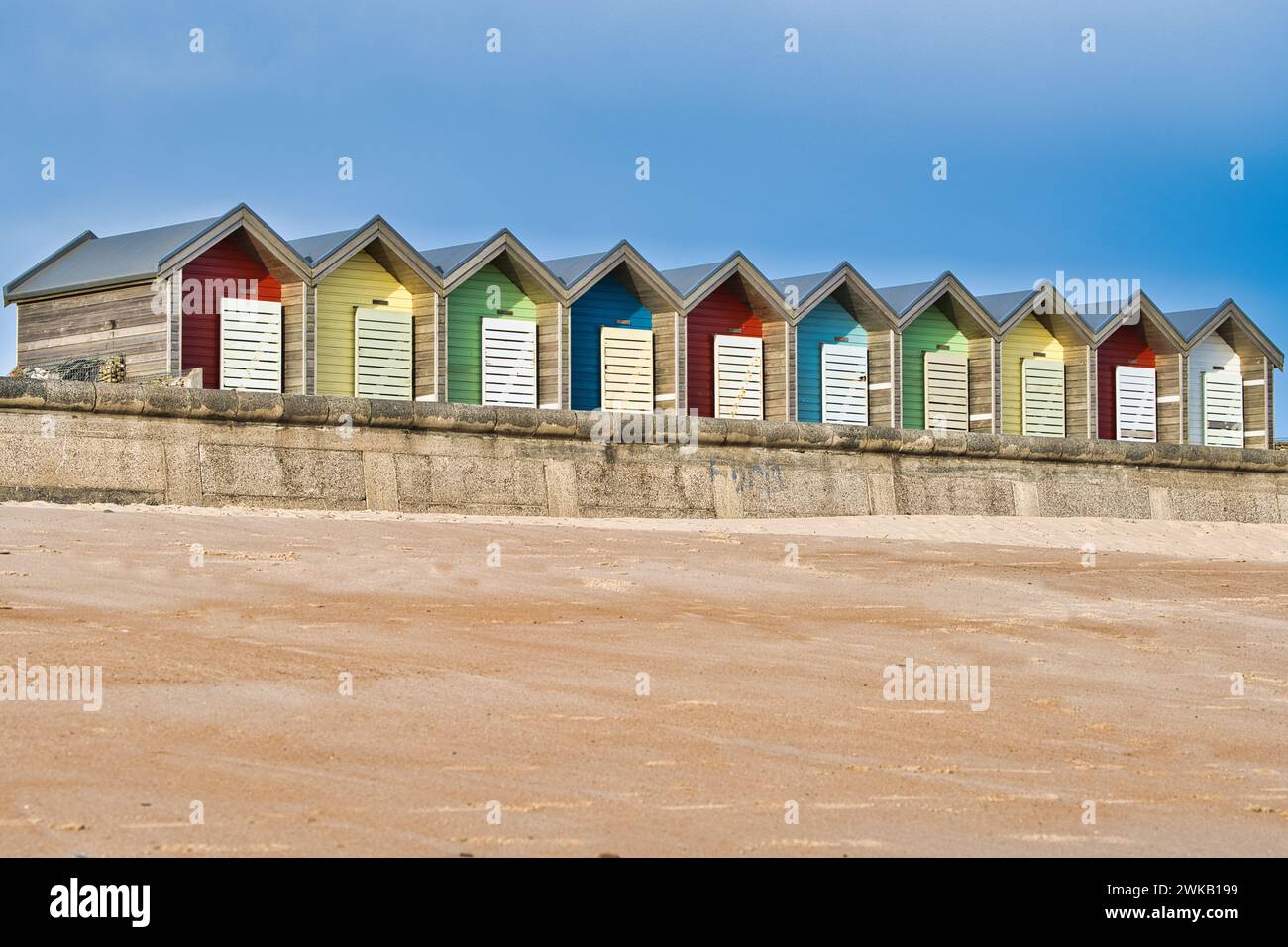 Cabanes de plage aux couleurs vives debout sur une promenade en bord de mer Banque D'Images