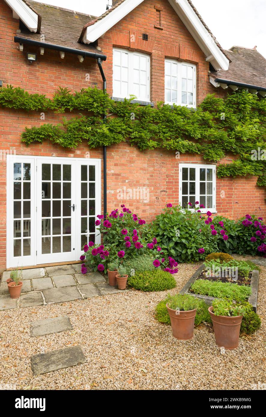 Maison britannique et jardin avec patio et portes françaises. Chalet ou jardin de cour (arrière-cour) avec gravier et pavage de pierre York Banque D'Images