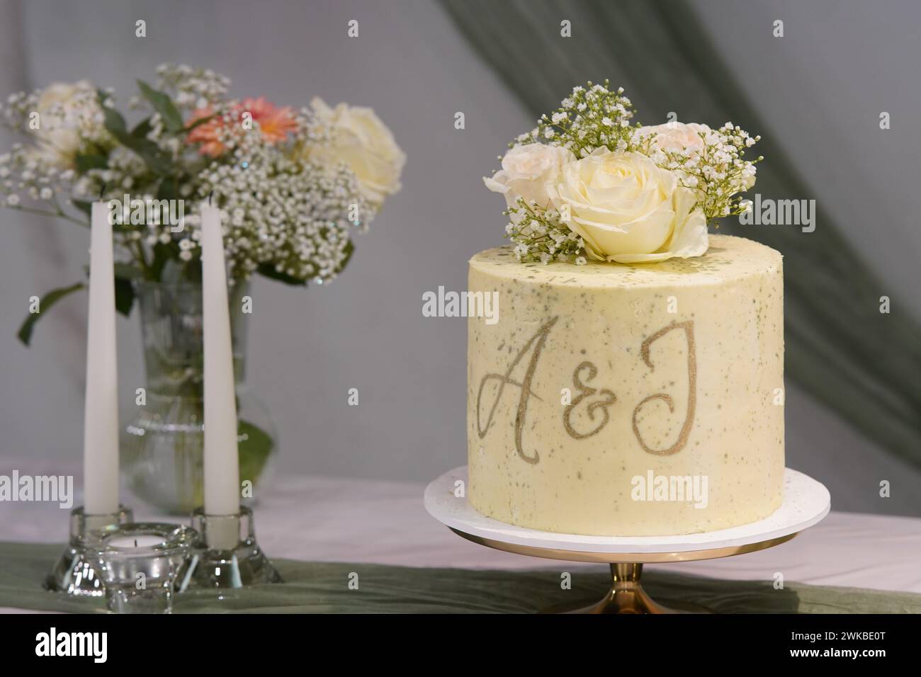 Le gâteau de mariage orné de fleurs délicates et arborant les initiales A&J ou A&I ajoute une touche élégante à la célébration. Banque D'Images