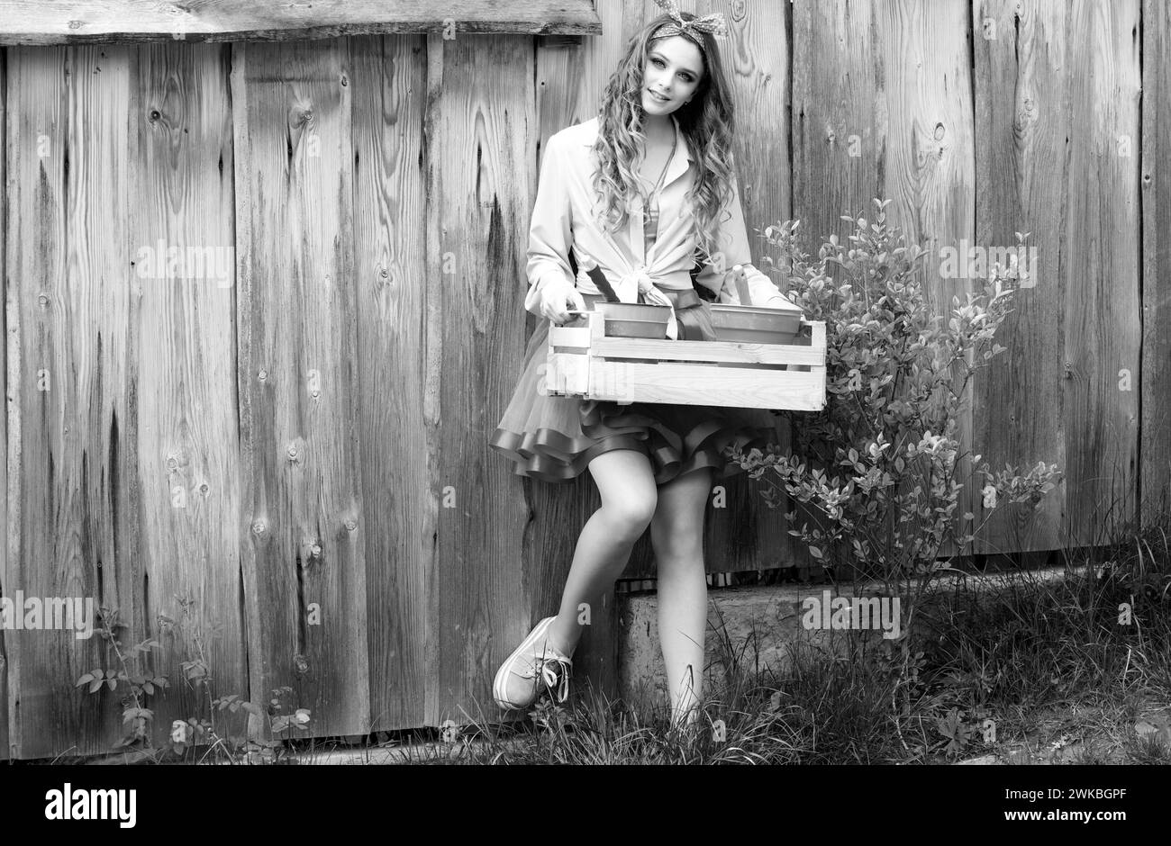 Bonne adolescente, jeune fille de l'adolescence tenant une caisse en bois avec des pots de la ferme. Femme plantant des fleurs en pot. Banque D'Images