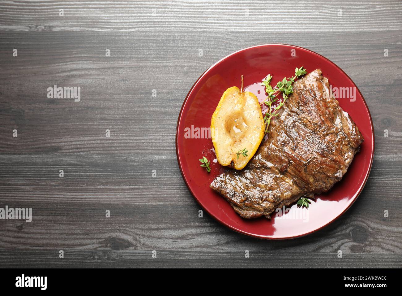 Délicieuse viande de bœuf rôtie, poire caramélisée et thym sur table en bois gris, vue de dessus. Espace pour le texte Banque D'Images