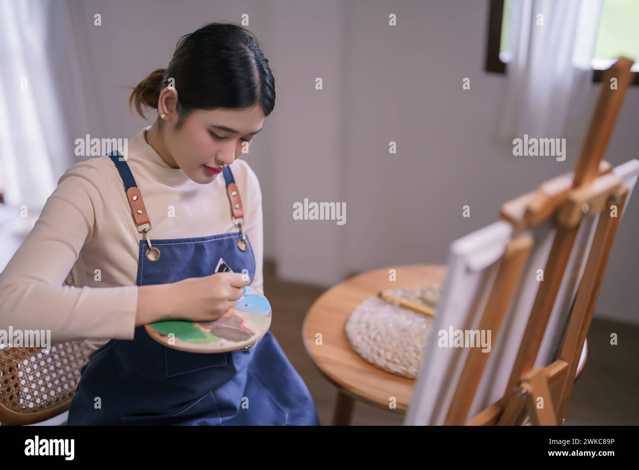 Jeune artiste féminine asiatique presser la couleur hors du tube sur la palette de couleurs pour peindre des œuvres d'art sur toile. Banque D'Images