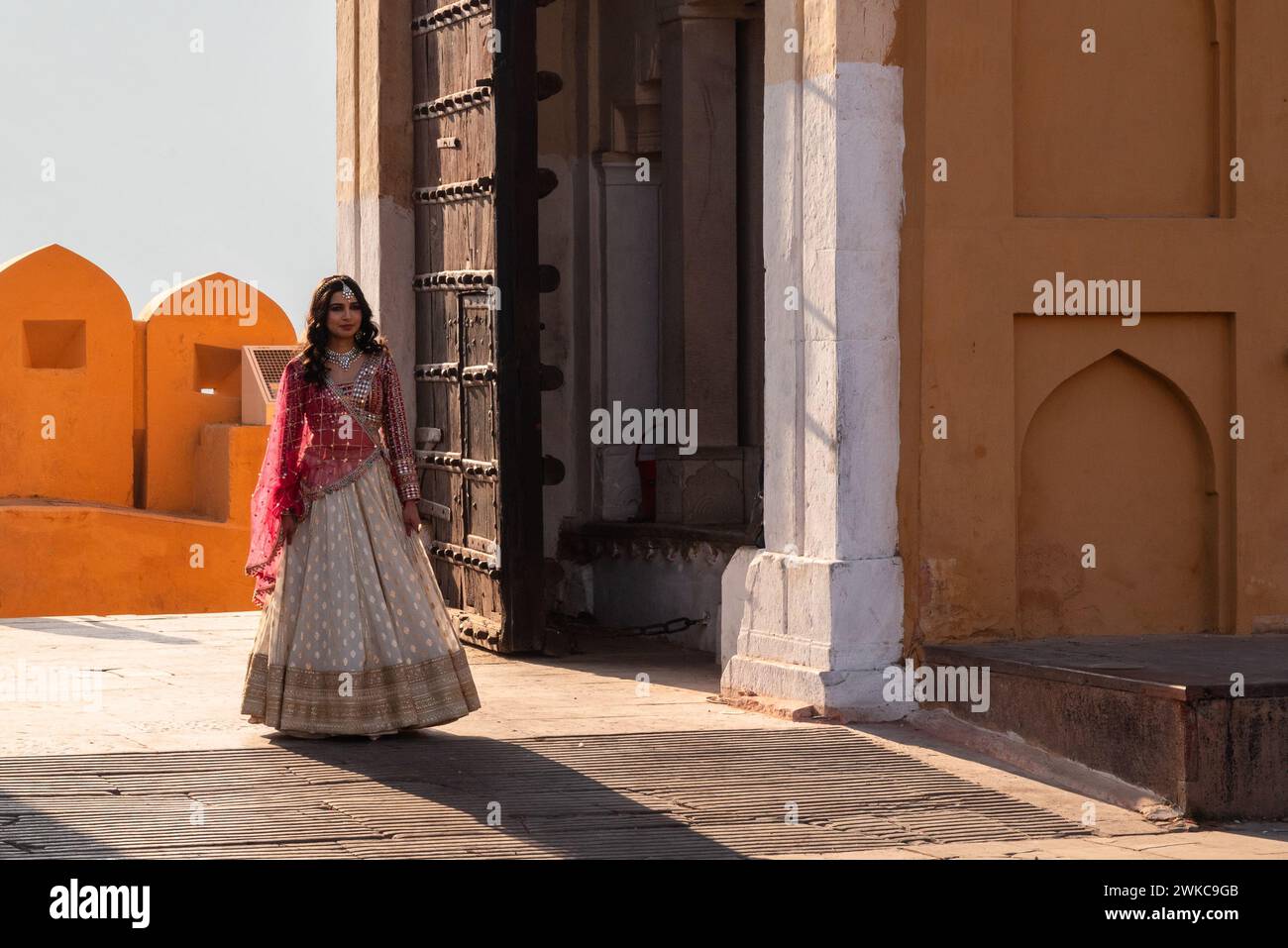 Jaipur, Inde 16 février 2024 mariée indienne posant pour une séance photo dans une robe de mariée traditionnelle rouge et or à Amer Fort Banque D'Images