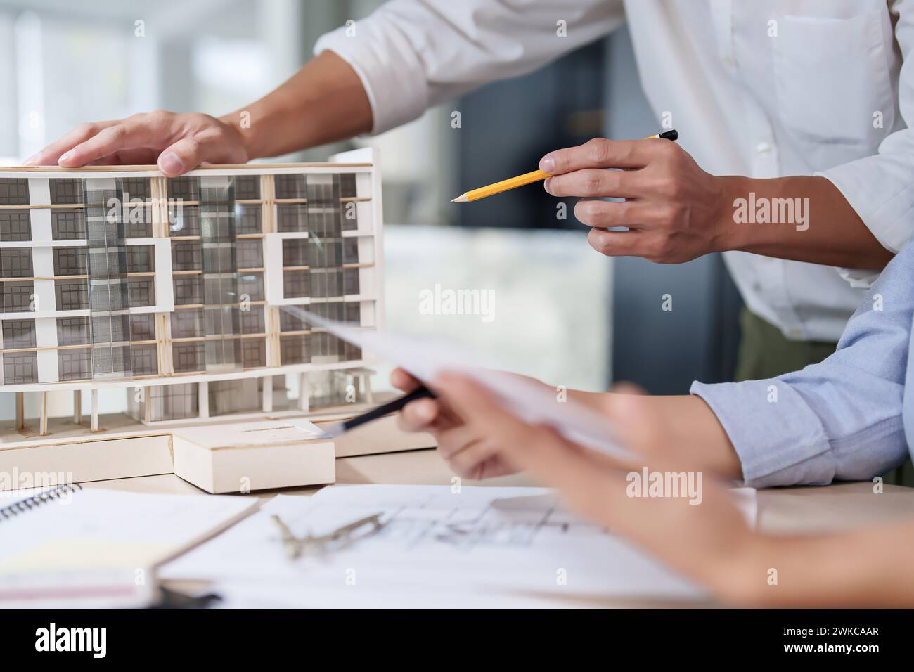 Deux ingénieurs d'architecte asiatiques inspectant le modèle de bâtiment et le plan de dessin du plan d'architecture tout en discutant pour concevoir un nouveau projet sur buil Banque D'Images
