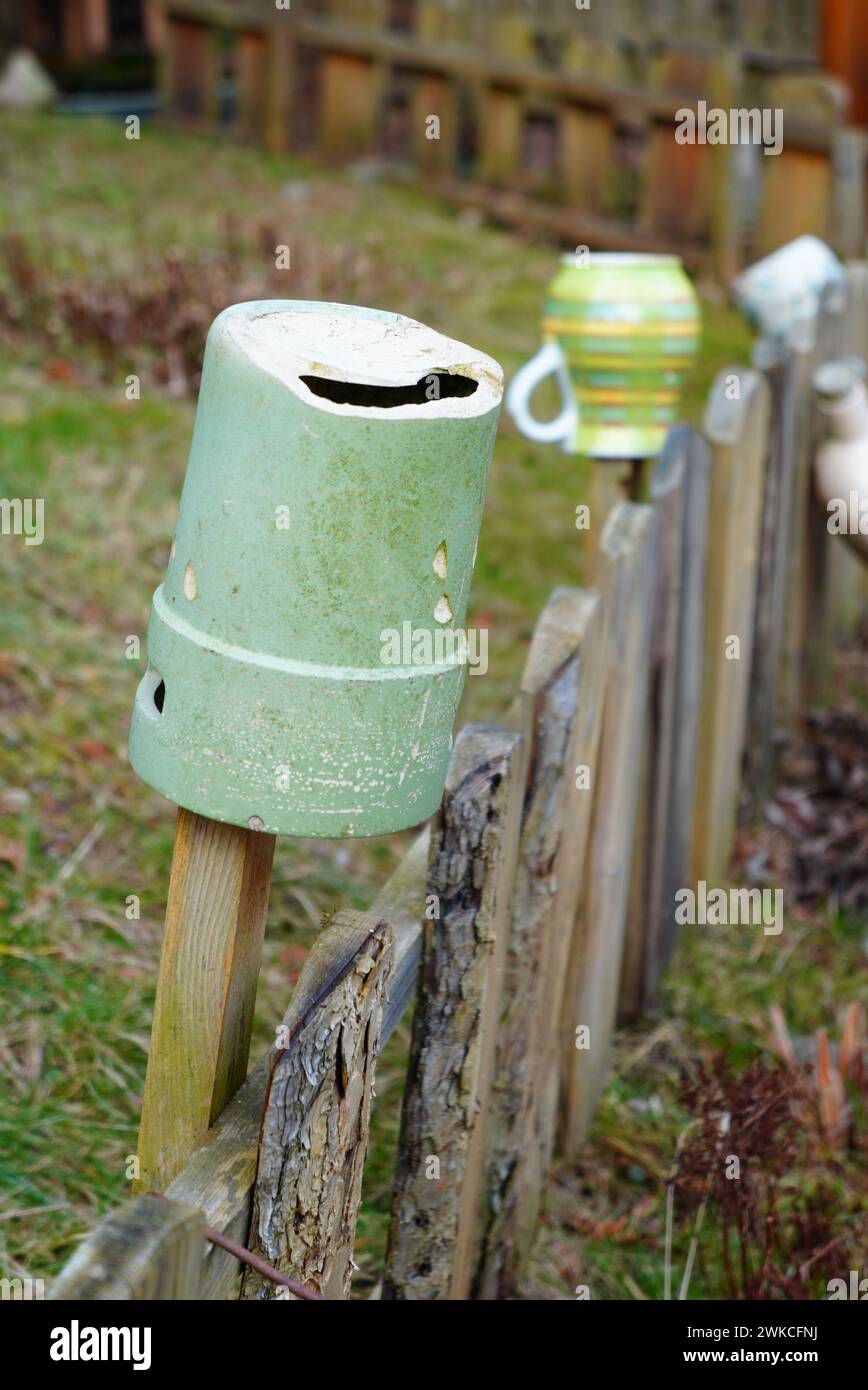 Poubelle verte montée sur poteau en bois parmi divers objets Banque D'Images