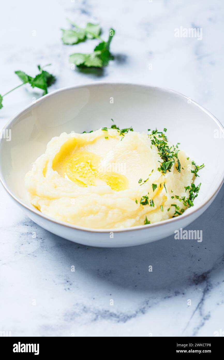 Purée de pommes de terre classique avec beurre et herbes, fond de marbre blanc. Banque D'Images