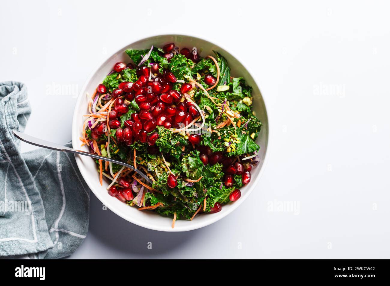 Détox salade végétalienne avec chou frisé, légumes, sauce grenade et tahini, fond blanc. Banque D'Images