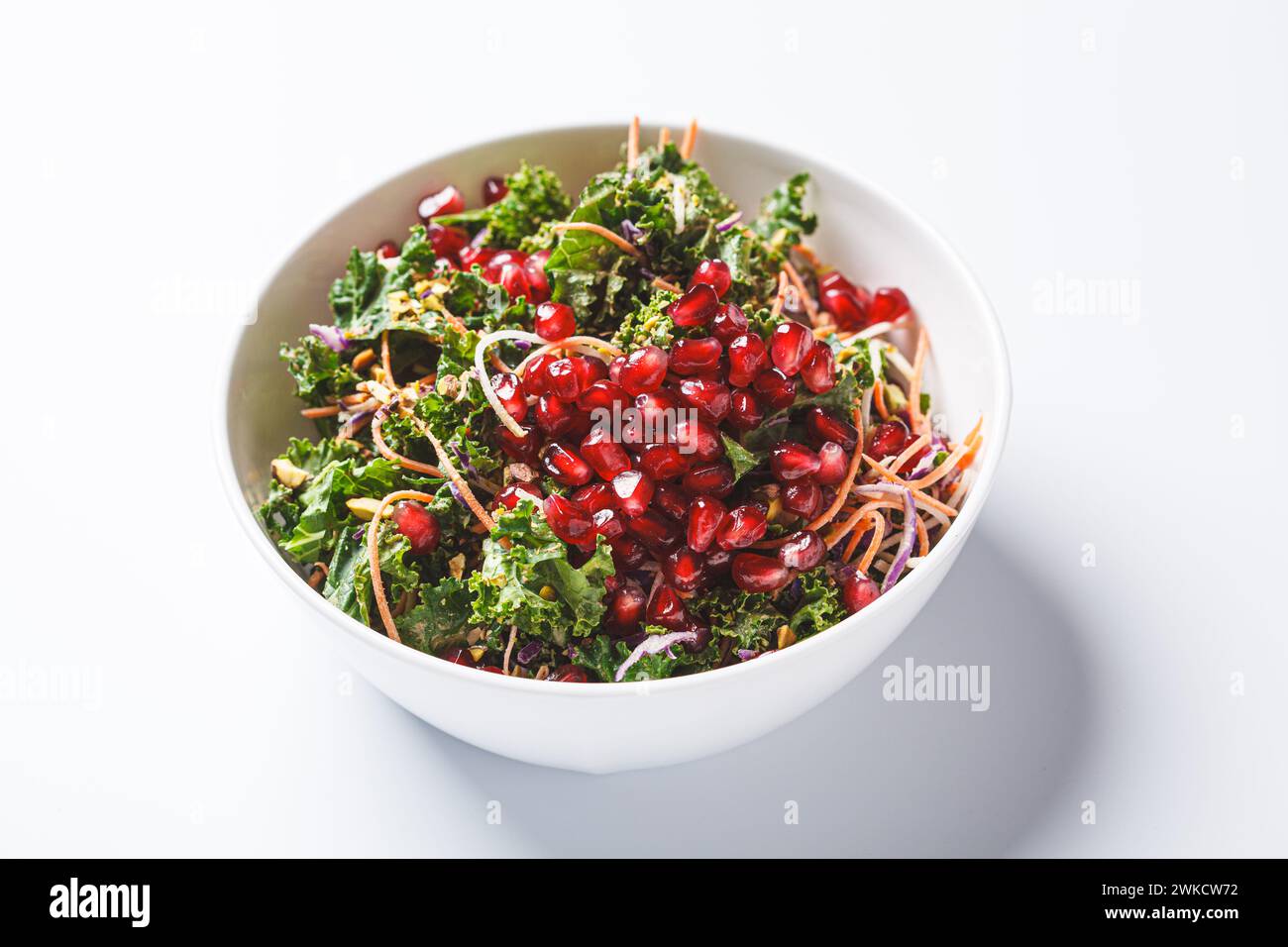 Détox salade végétalienne avec chou frisé, légumes, sauce grenade et tahini, fond blanc. Banque D'Images