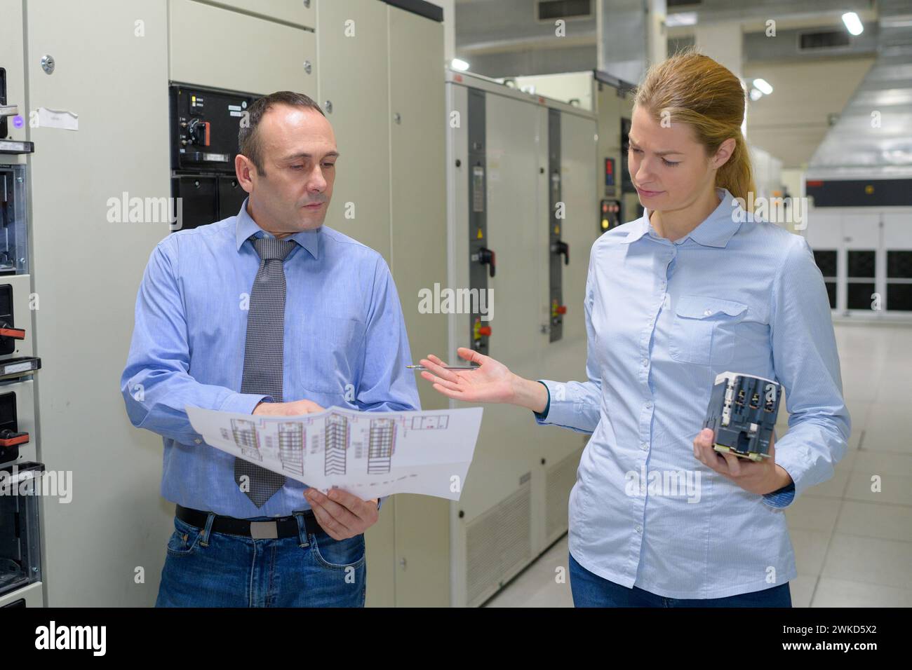 les techniciens informatiques examinent la paperasserie avec confusion Banque D'Images