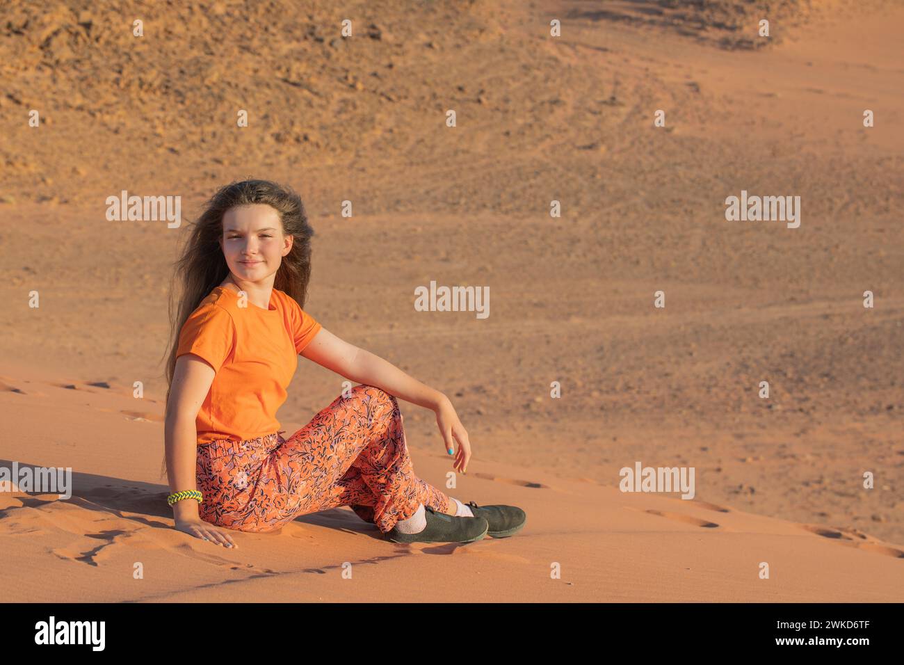 La jeune fille est assise sur le sable rouge dans le désert de Wadi Rum, Jordanie Banque D'Images