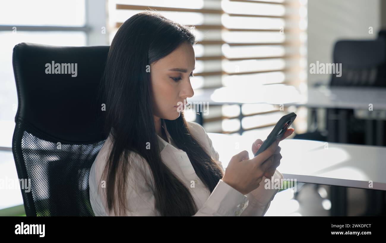 Femme d'affaires sérieuse naviguant le téléphone dans le bureau caucasien calme fille confiante ennuyeuse femme d'affaires tapant chatter dans les médias sociaux mobiles femme Banque D'Images