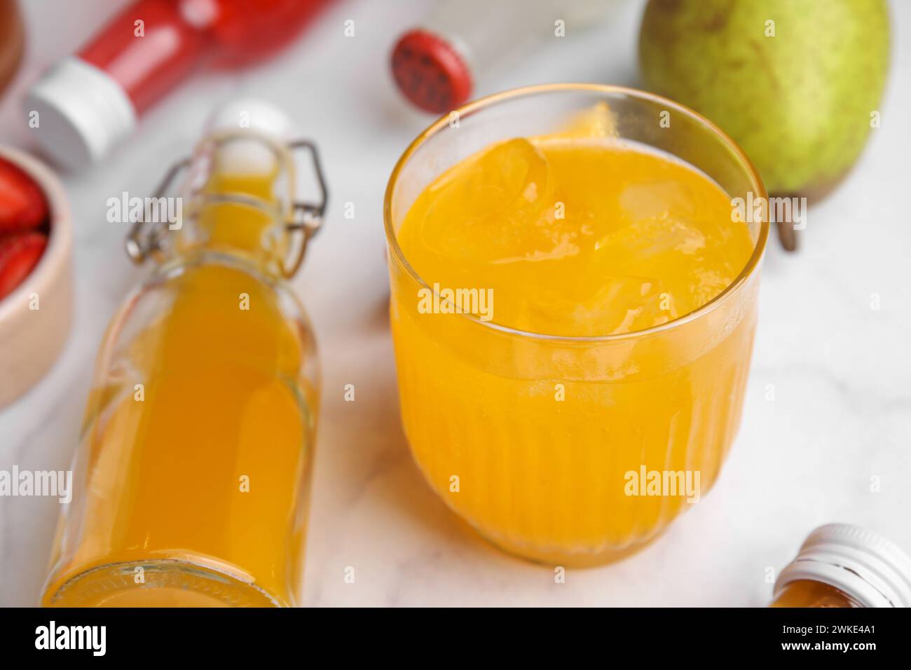 Savoureux kombucha en verre et bouteilles sur table blanche, gros plan Banque D'Images