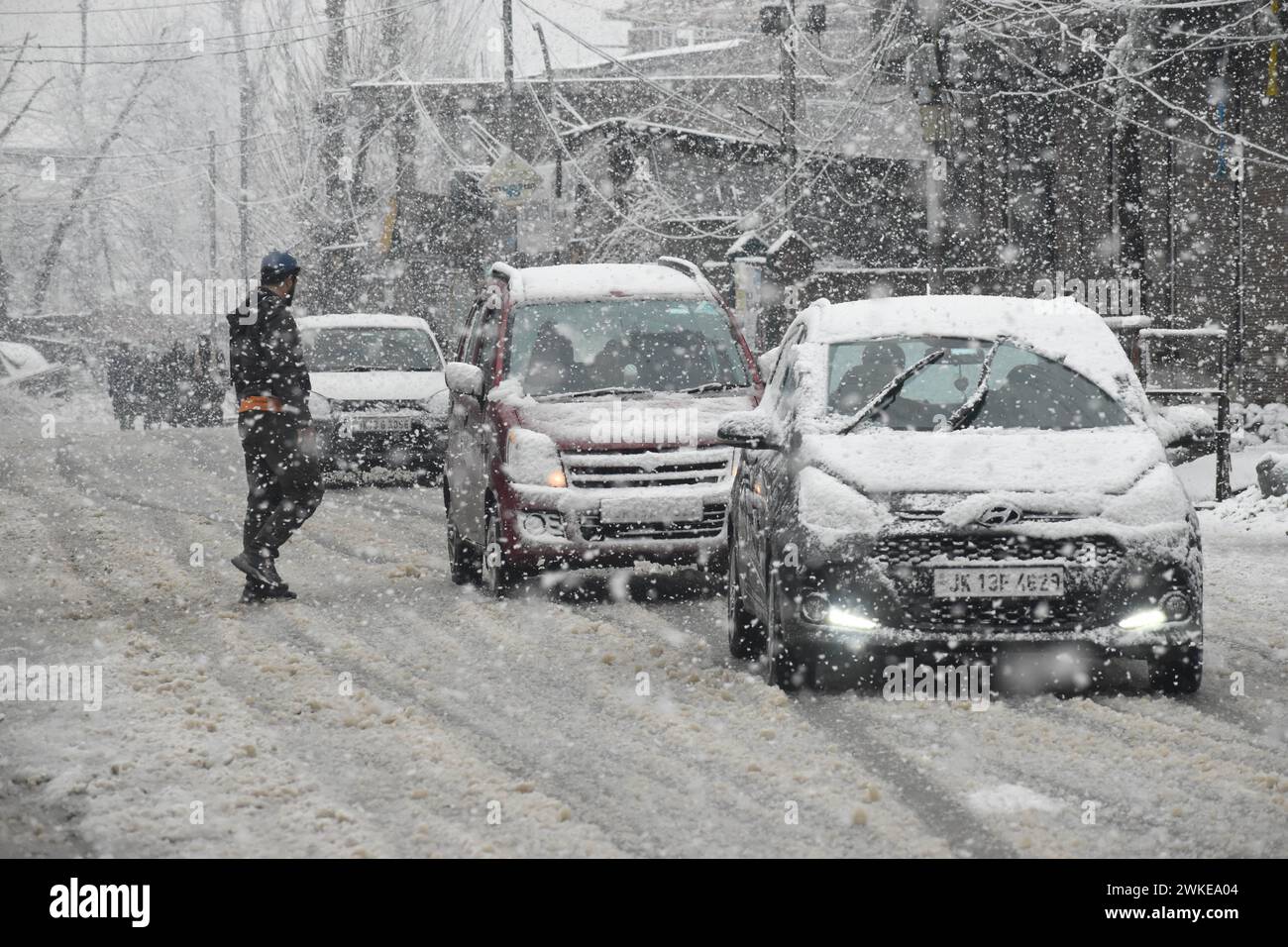 Srinagar, Inde. 20 février 2024. Au milieu d'un spectacle hivernal à Srinagar, Jammu-et-Cachemire, en Inde, les piétons naviguent dans les rues enneigées tandis que les véhicules se frayent prudemment un chemin à travers les fortes chutes de neige le 20 février 2024. Les prévisions du Département météorologique concernant des chutes de neige importantes du 18 au 20 février ajoutent au charme hivernal de la scène. (Photo de Danish Showkat/Sipa USA) crédit : Sipa US/Alamy Live News Banque D'Images