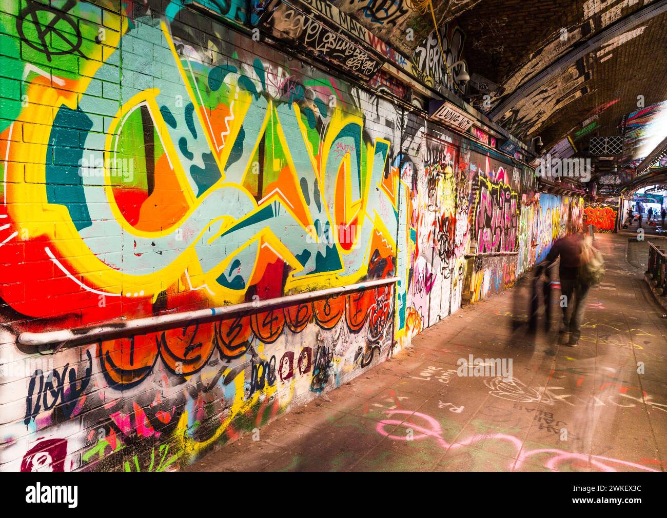 Image longue exposition de gens marchant dans le tunnel de Leake Street entouré d'œuvres d'art de rue et de graffitis. Banque D'Images