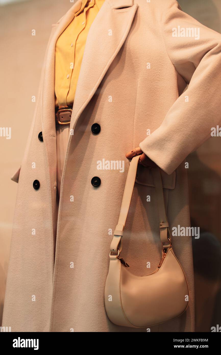 Détails d'un manteau beige saisonnier, d'une chemise jaune vif et d'un petit sac à main. Vêtements et accessoires de mode décontractés pour femmes Banque D'Images