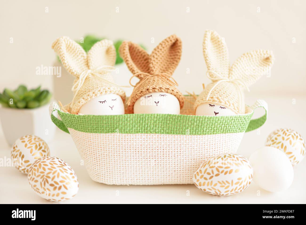 Oeufs de Pâques dans des chapeaux tricotés au crochet avec des oreilles de lapin dans le nid. Concept de célébration de Pâques Banque D'Images