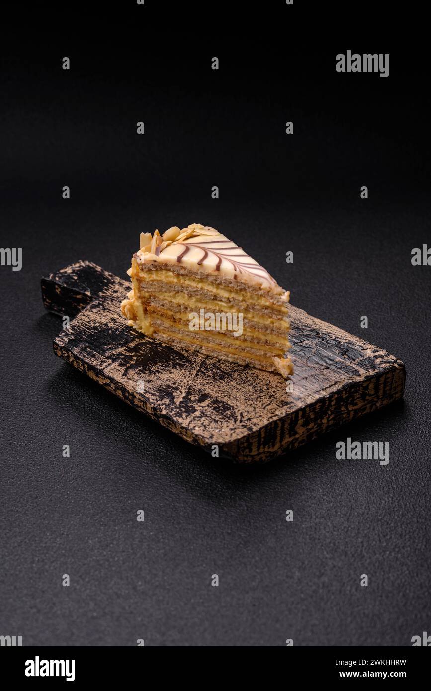 Morceau de délicieux gâteau doux esterhazy avec des noix et de la crème sur un fond de béton foncé Banque D'Images