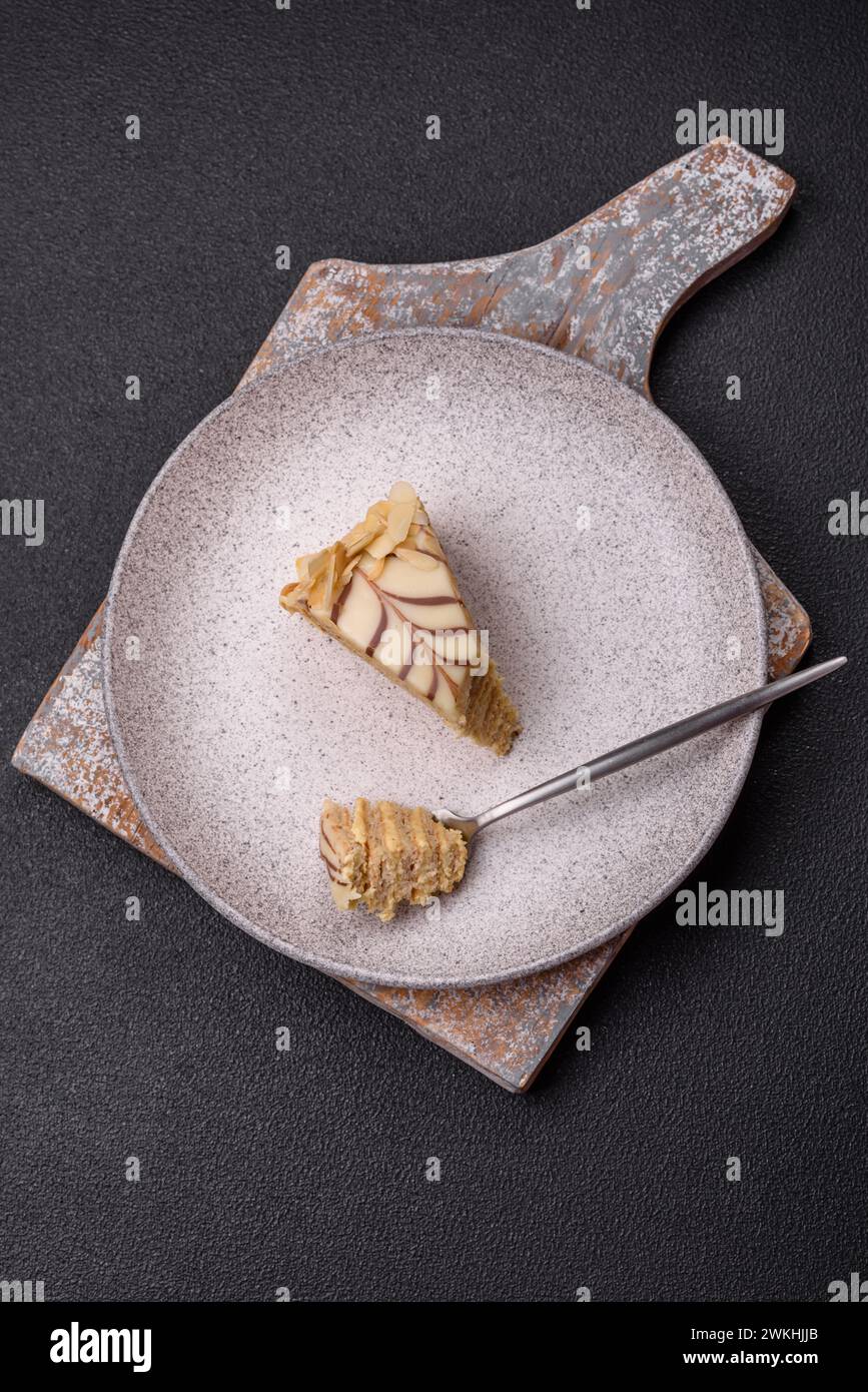 Morceau de délicieux gâteau doux esterhazy avec des noix et de la crème sur un fond de béton foncé Banque D'Images