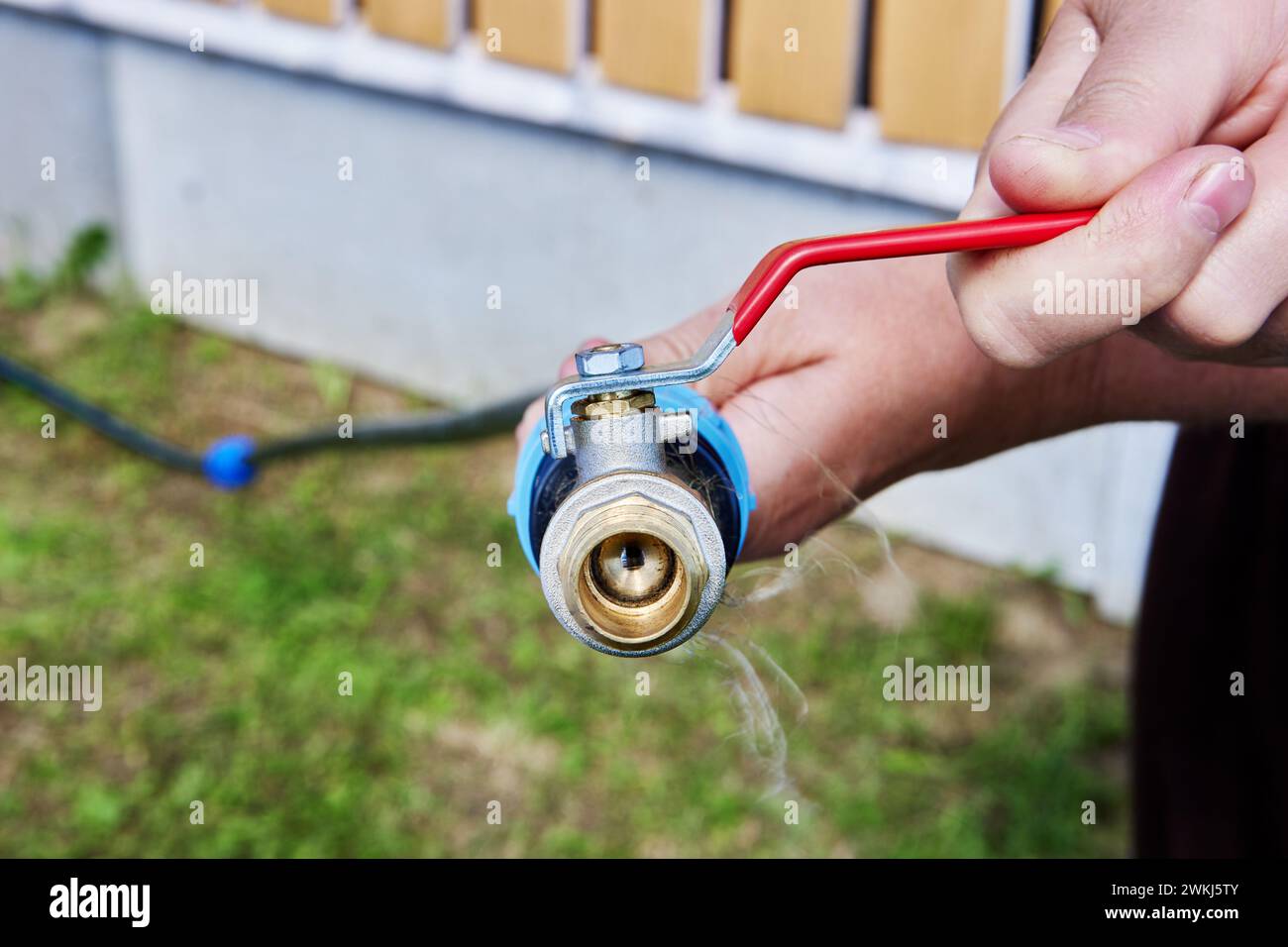 Robinet à boisseau sphérique en métal avec levier est fixé à l'extrémité du tuyau HDPE à l'aide d'un adaptateur avec pince de compression, le système est utilisé pour arroser le jardin. Banque D'Images