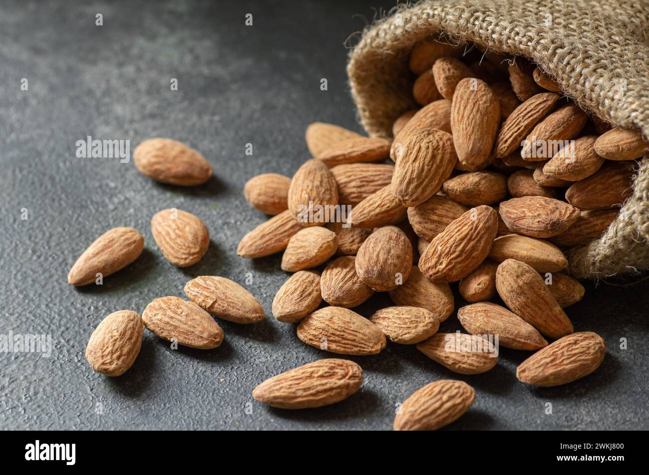 Délicieuses amandes douces dans un bol en bois ou un sac en toile de jute sur fond rustique, noix d'amande rôtie, nourriture saine Banque D'Images