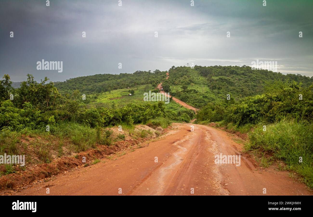 Une route de terre rouge après de fortes pluies à travers la forêt et la nature sauvage près de Cholesamvula en Tanzanie. Banque D'Images
