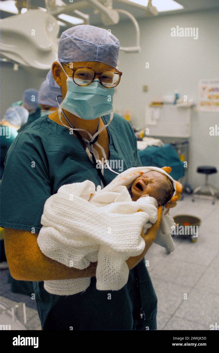 NHS 1980s Doctor Phil Hammond tenant un bébé qui vient de naître par césarienne au Royal United Hospital Bath. Somerset, Angleterre des années 1988 1980 Royaume-Uni HOMER SYKES Banque D'Images