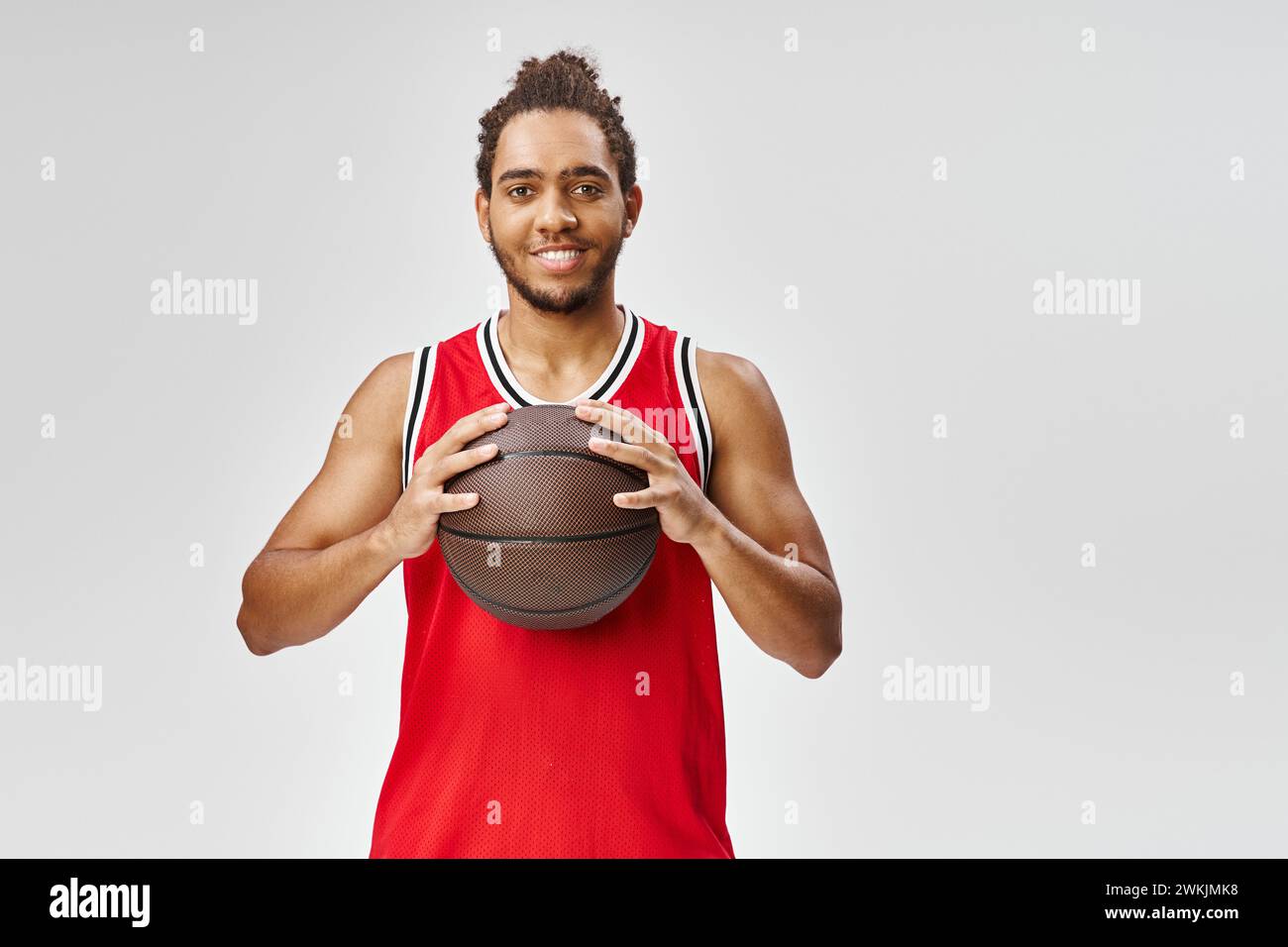 joyeux homme afro-américain en vêtements de sport posant avec le basket-ball et regardant la caméra Banque D'Images