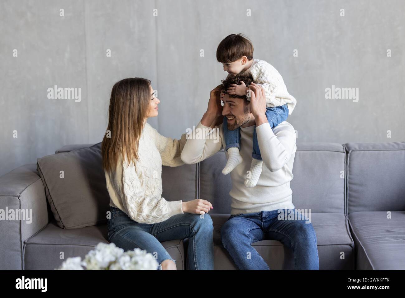 Famille gaie s'amuser et jouer avec son petit fils tout en se détend sur le canapé dans le salon Banque D'Images