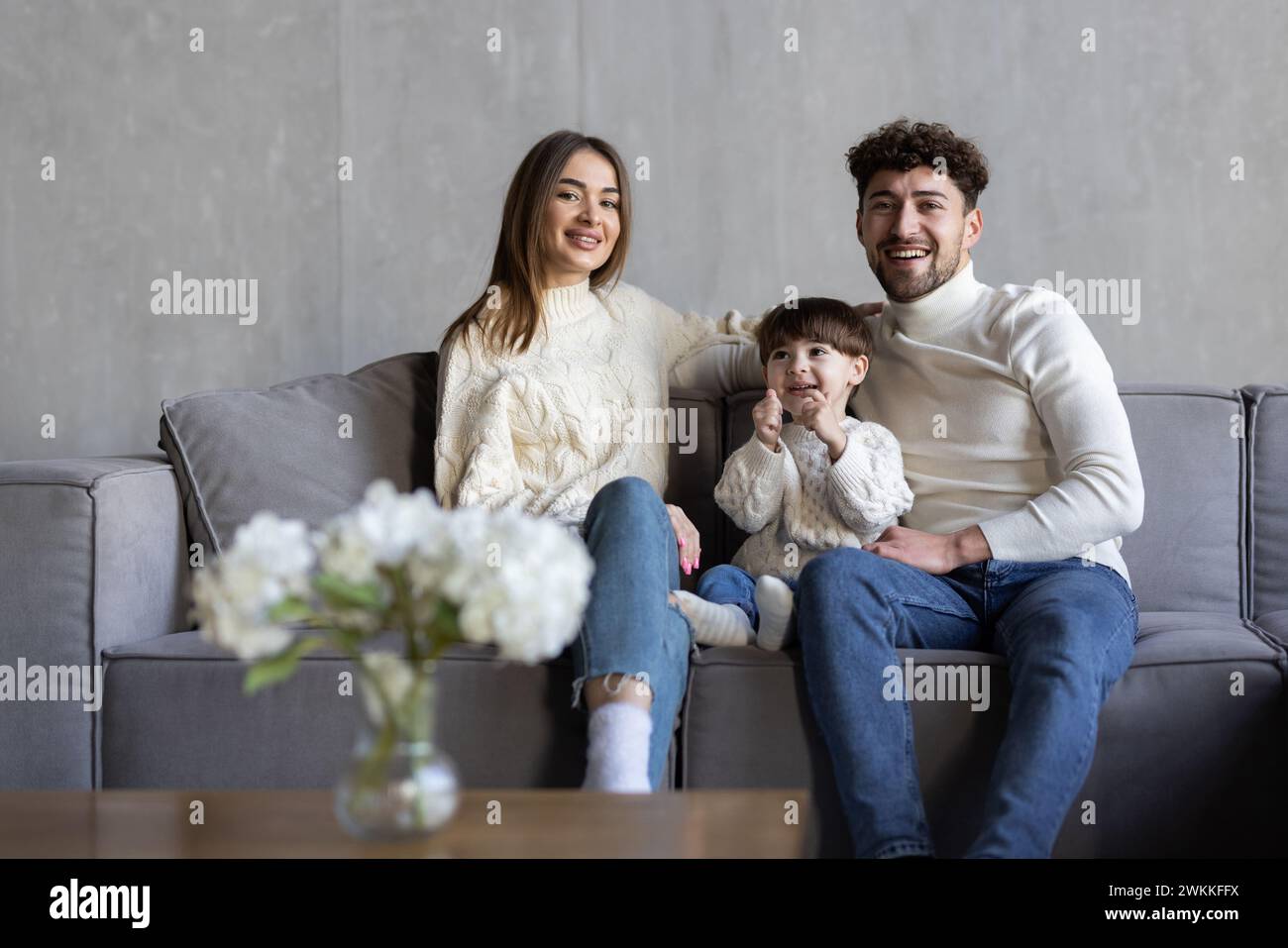Portrait d'une famille heureuse en faisant des gestes pouces vers le haut tout en étant assis sur le canapé Banque D'Images
