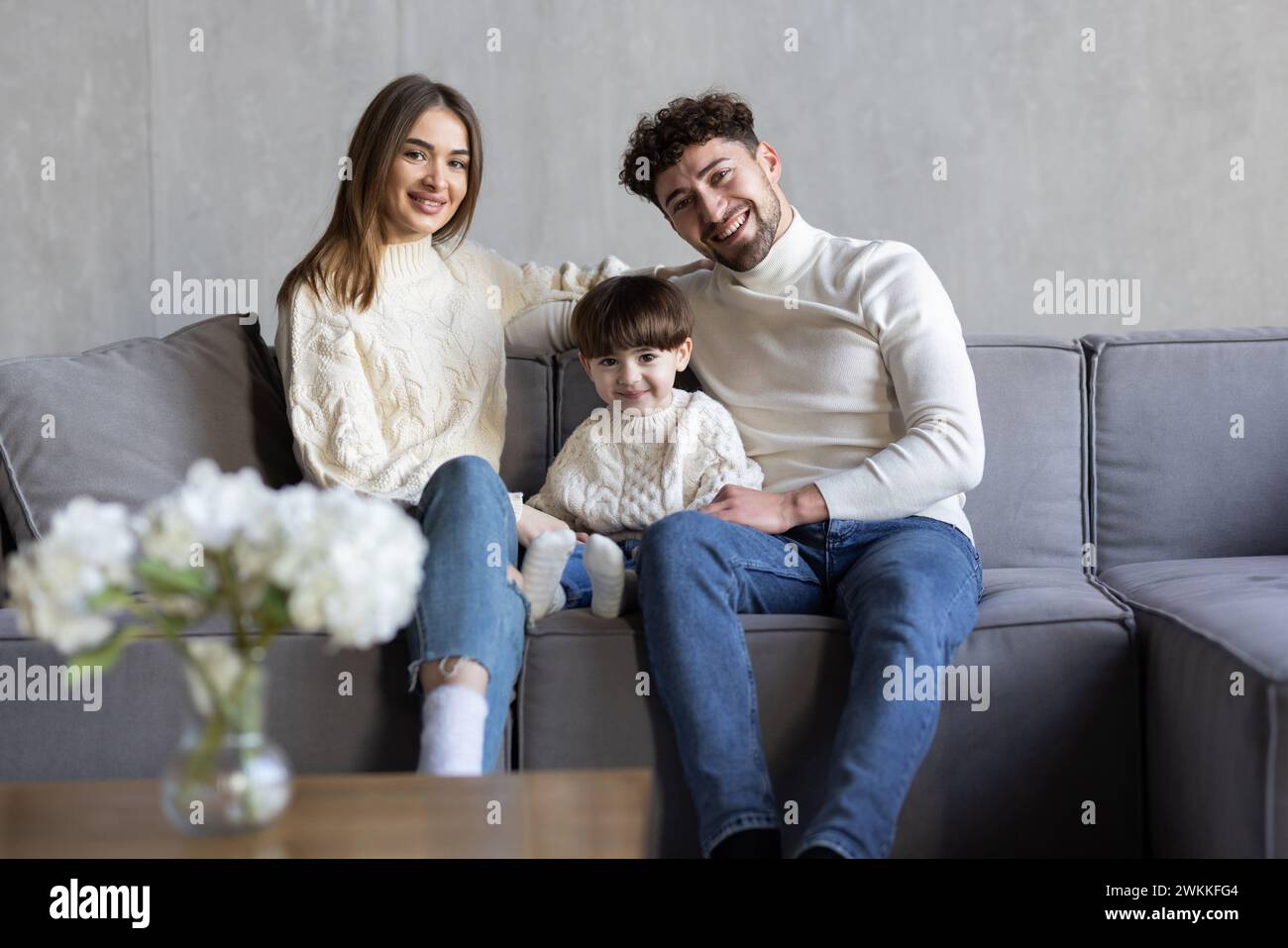 La famille joyeuse passent du temps drôle tout en étant assis sur divan dans une pièce lumineuse. Concept de parentalité heureuse Banque D'Images