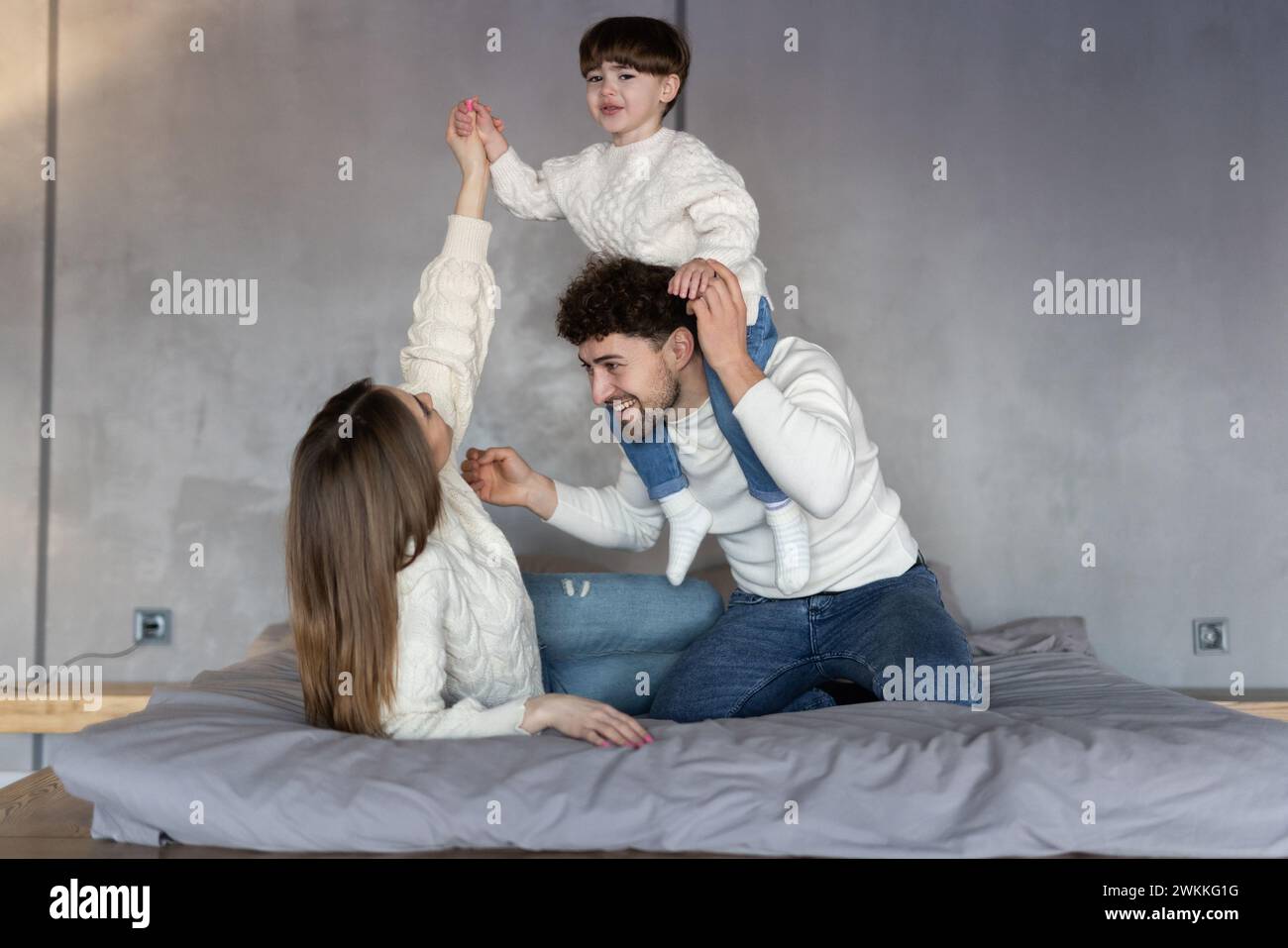 Heureux parents de jouer avec leur fils sur le lit Banque D'Images