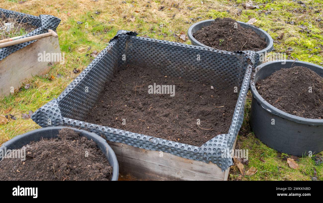 Vidé le lit surélevé dans le jardin en préparation du dépôt avec du fumier de cheval avec des seaux de terre autour de lui Banque D'Images