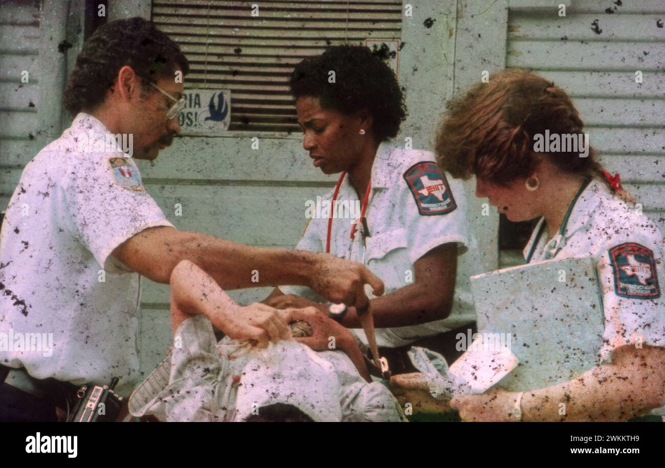 Des techniciens médicaux d'urgence, hommes et femmes, dispensent des soins à la victime d'une agression violente. ©Bob Daemmrich Banque D'Images