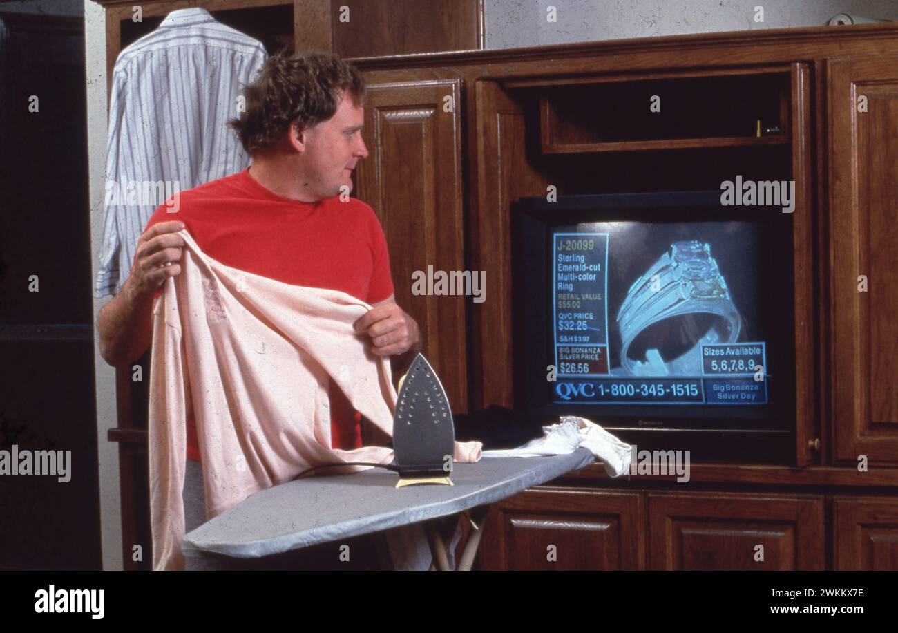 Austin Texas USA, 1991 : homme regarde la chaîne de shopping à la télévision tout en repassant. M. ©Bob Daemmrich Banque D'Images