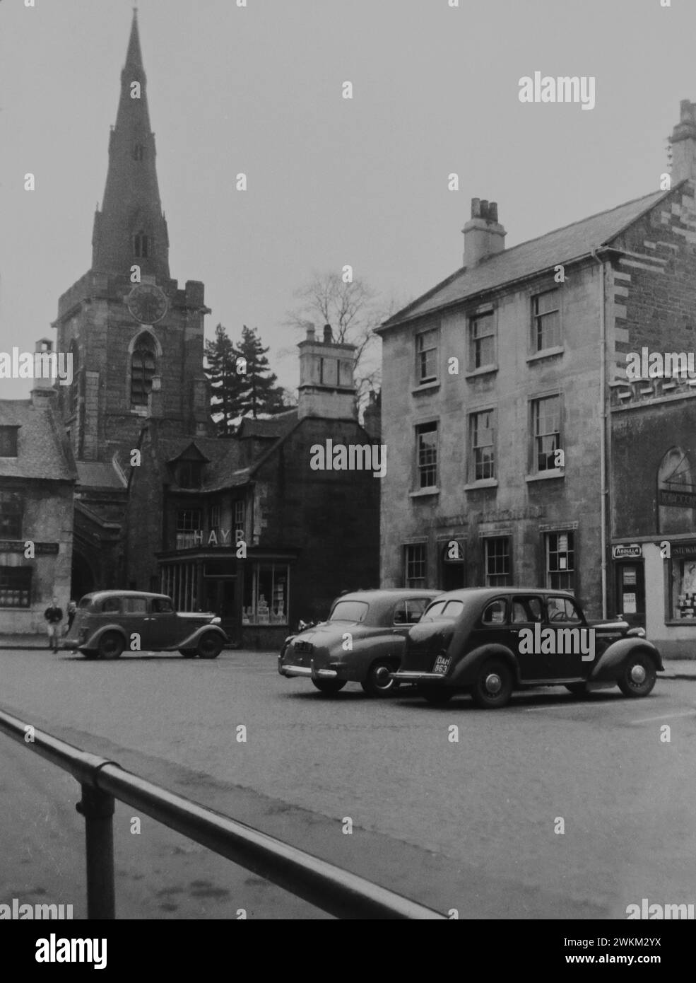 Uppingham Market place, Rutland, dans les années 1950 L'image montre l'église Saint-Pierre et Saint-Paul en arrière-plan. les voitures des années 1950 sont garées sur la place du marché. Le bâtiment de trois étages classé Grade II était autrefois la chirurgie des médecins et est maintenant le bureau de poste. Cette photo a été prise à partir du négatif original et il y a peut-être des imperfections. Banque D'Images