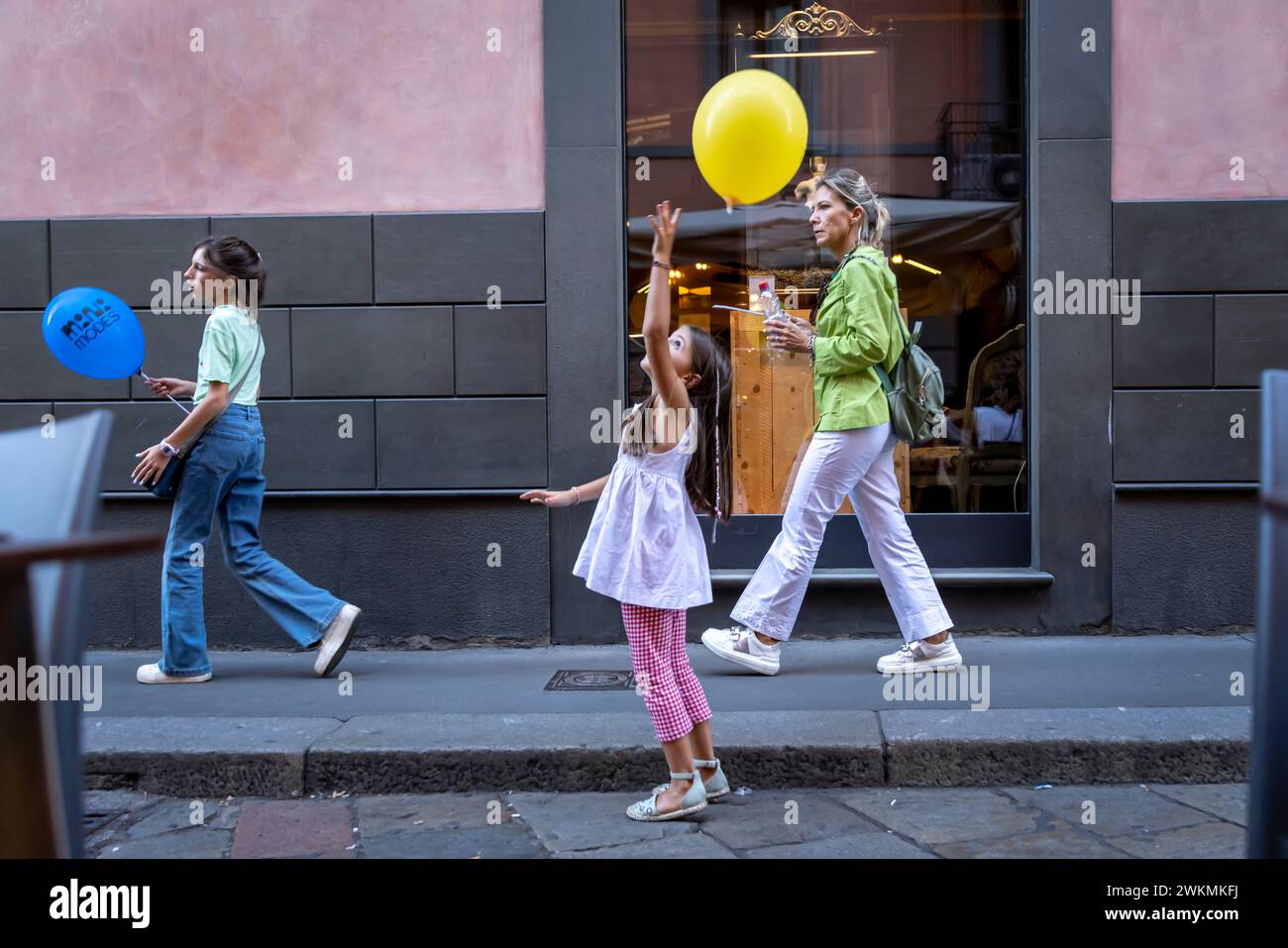 Une jeune fille joue avec un ballon alors qu'elle marche dans une rue du quartier Brera de Milan. Banque D'Images