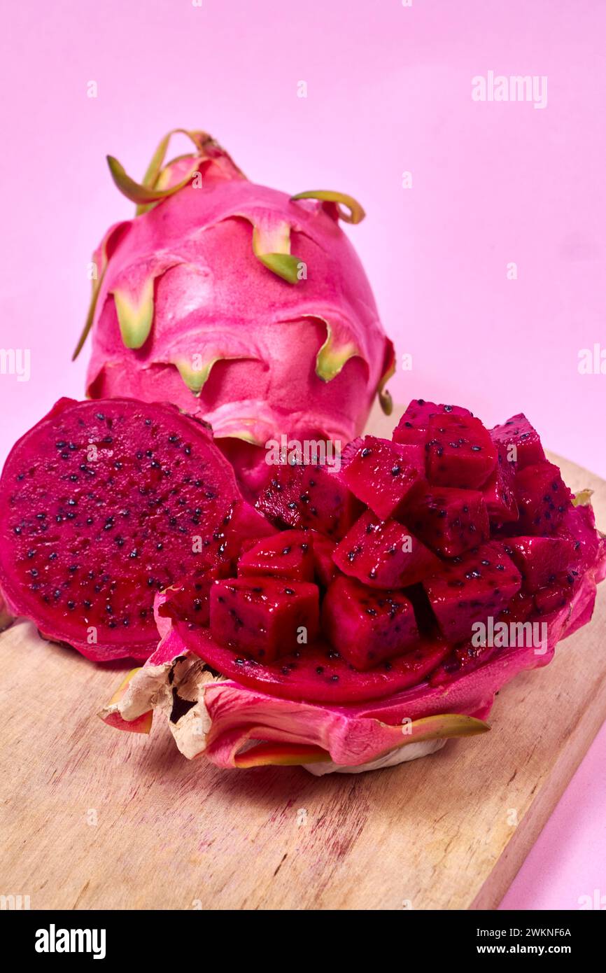 Ensemble de fruits de dragon rouge avec service appétissant isolé sur fond rose. Vue de dessus, main Banque D'Images