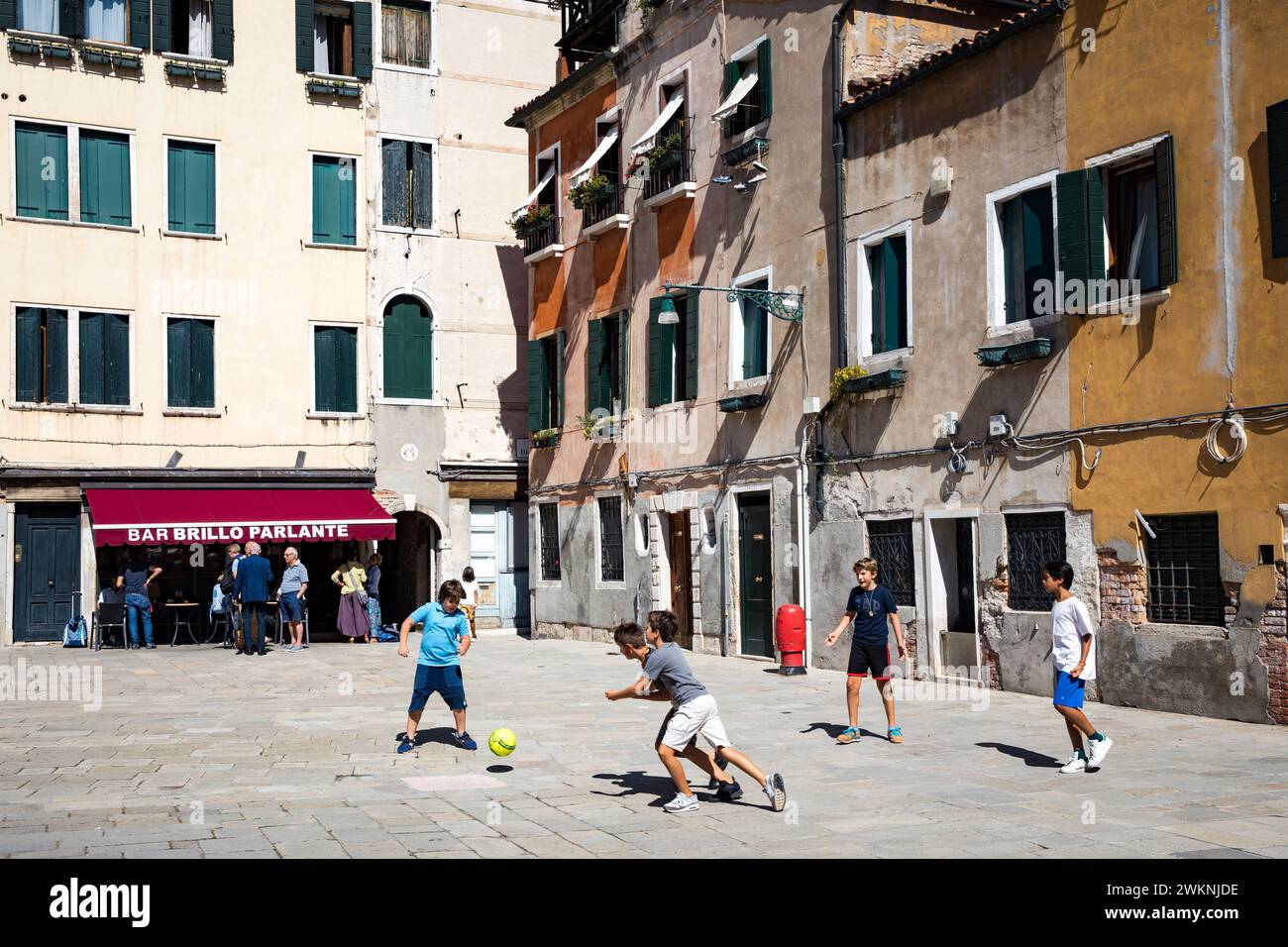 Les enfants jouent au soccer dans une place du quartier Dorsoduro en fin d'après-midi d'été. Banque D'Images