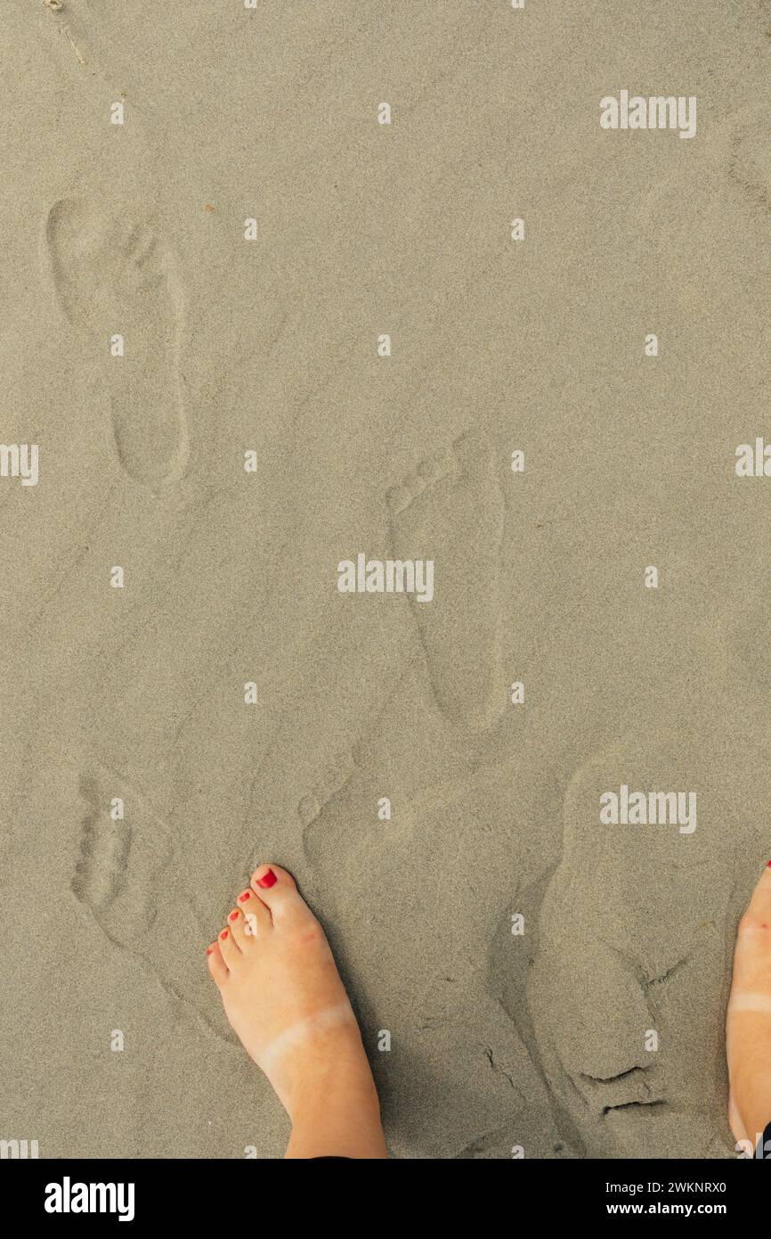 empreintes de pieds et pieds avec pédicure rouge sur la plage de sable Banque D'Images