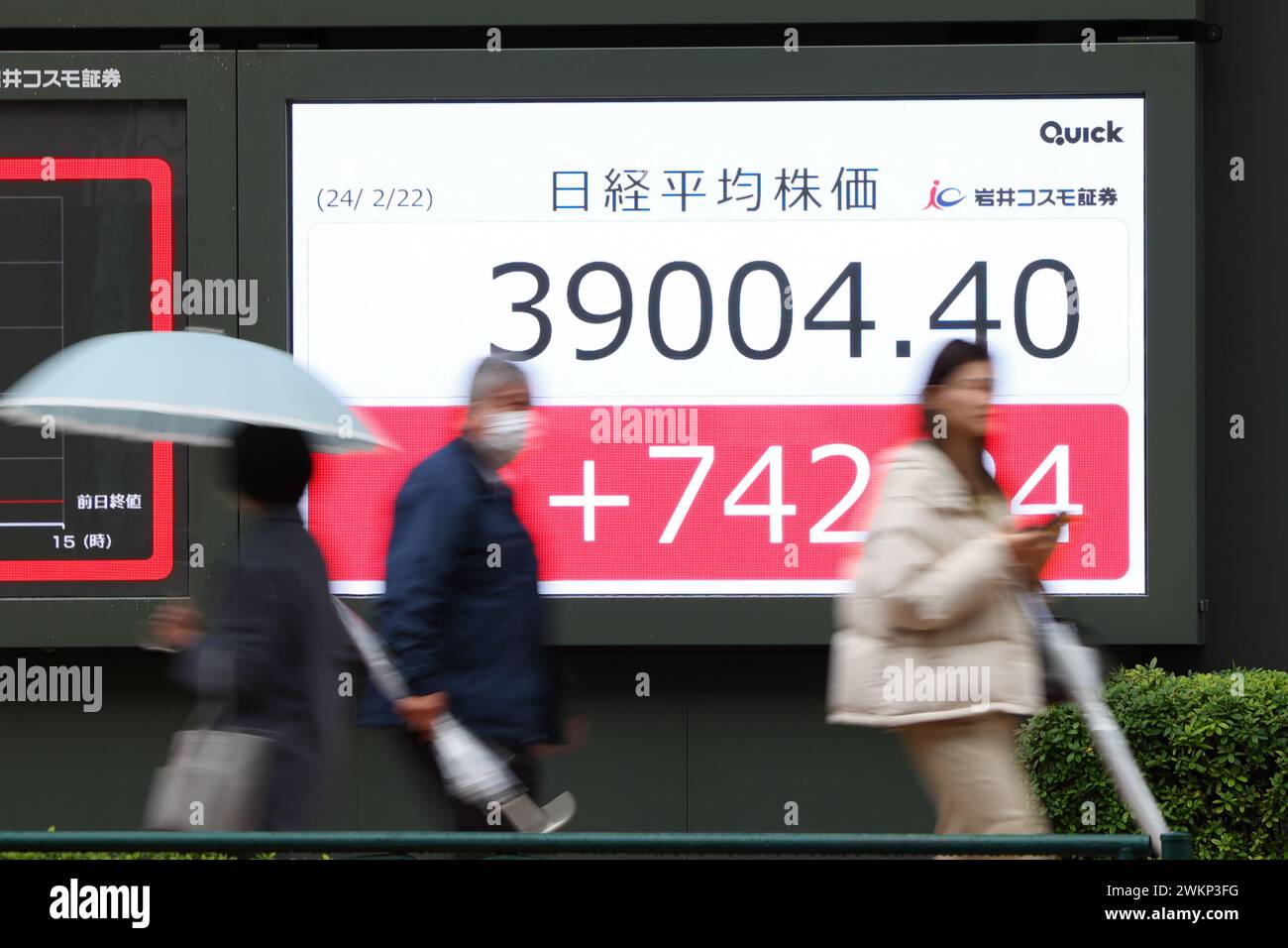 Les passants marchent devant la moyenne des parts de Nikkei du Japon affichée sur un panneau à Tokyo, Japon, le 22 février 2024. La moyenne des actions Nikkei a dépassé les 39 000 jeudi pour la première fois, battant le précédent record de tous les temps enregistré en 1989. Crédit : Yohei Osada/AFLO/Alamy Live News Banque D'Images