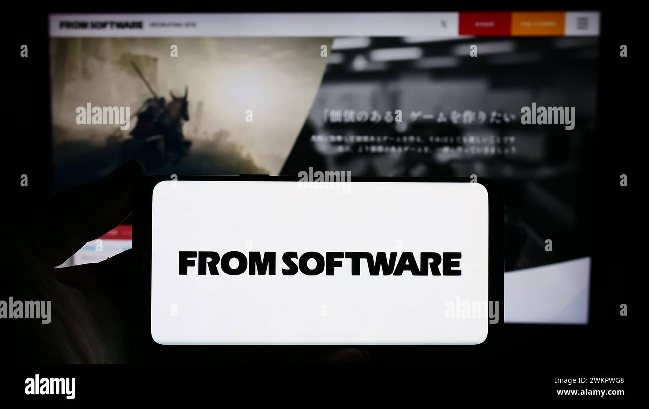 Personne tenant un smartphone avec le logo de la société japonaise de jeux vidéo FromSoftware Inc en face du site Web. Concentrez-vous sur l'affichage du téléphone. Banque D'Images