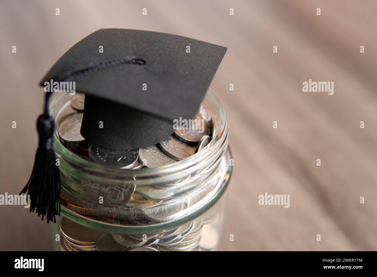 Pot en verre rempli de pièces de monnaie et un bouchon de graduation sur le dessus. Copier l'espace pour le texte. Concept d'épargne-études. Banque D'Images