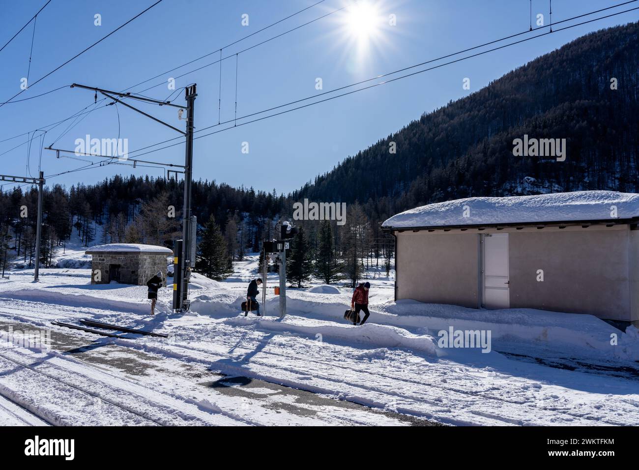 suisse, 01-13-2024Voici les gens qui marchent le long des voies d'une petite gare située en hauteur dans les montagnes couvertes de neige scintillante sous le soleil Banque D'Images