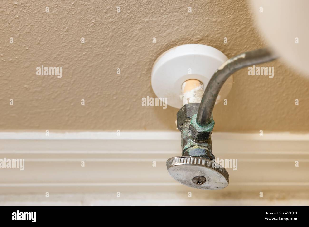 Maison résidentielle salle de bains WC robinet d'arrêt d'eau. Remplacement de l'ancienne tuyauterie de vanne de conduite d'alimentation murale des toilettes qui fuit. Banque D'Images