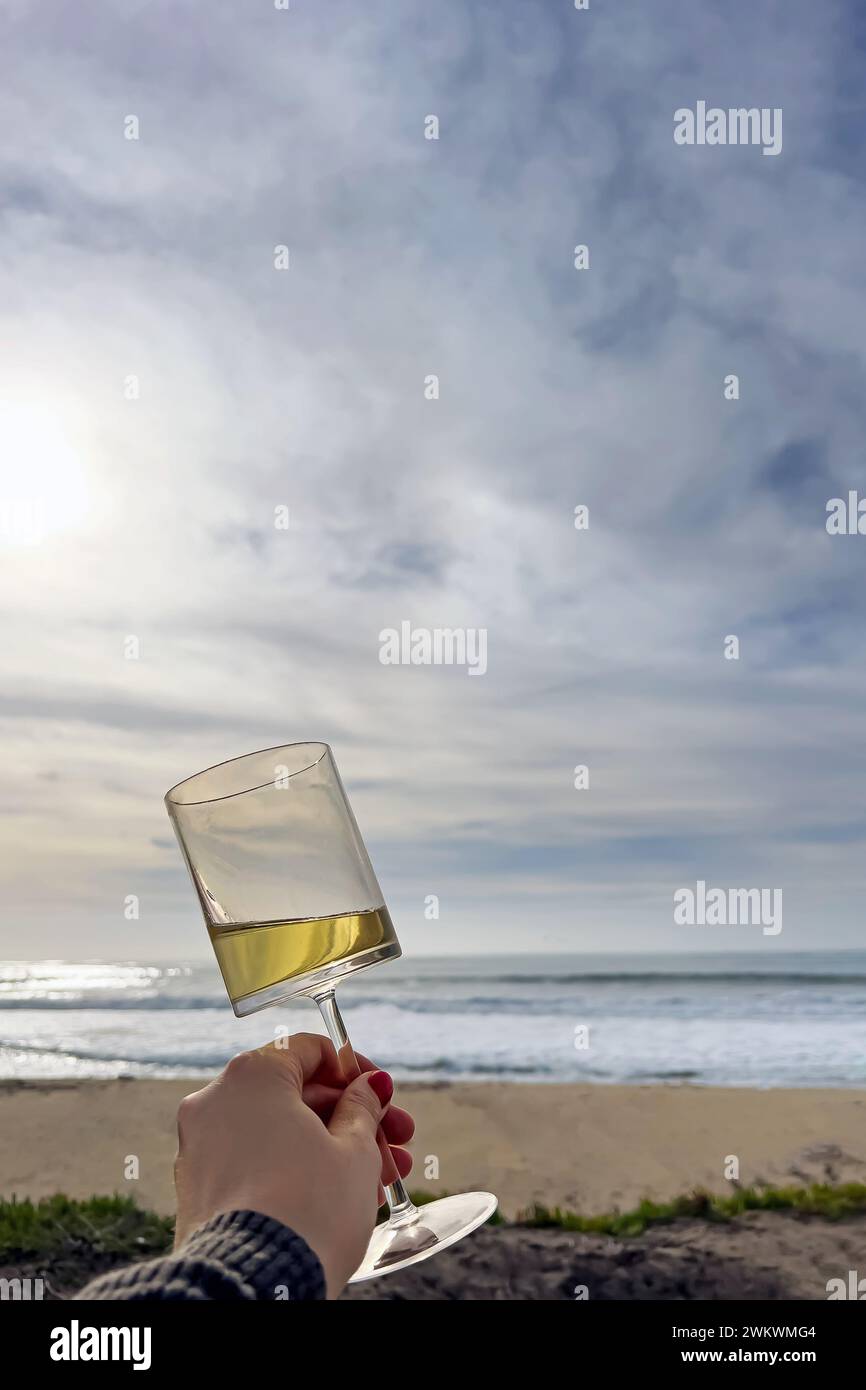 Main femelle tenant le verre de la gémissement blanc, pique-nique sur la plage Banque D'Images