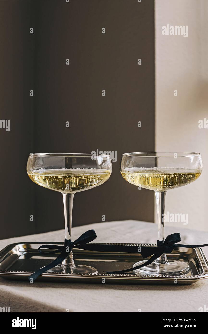 Deux coupés vitrés avec du vin mousseux décorés de noeuds en ruban de satin debout sur un élégant plateau en argent Banque D'Images