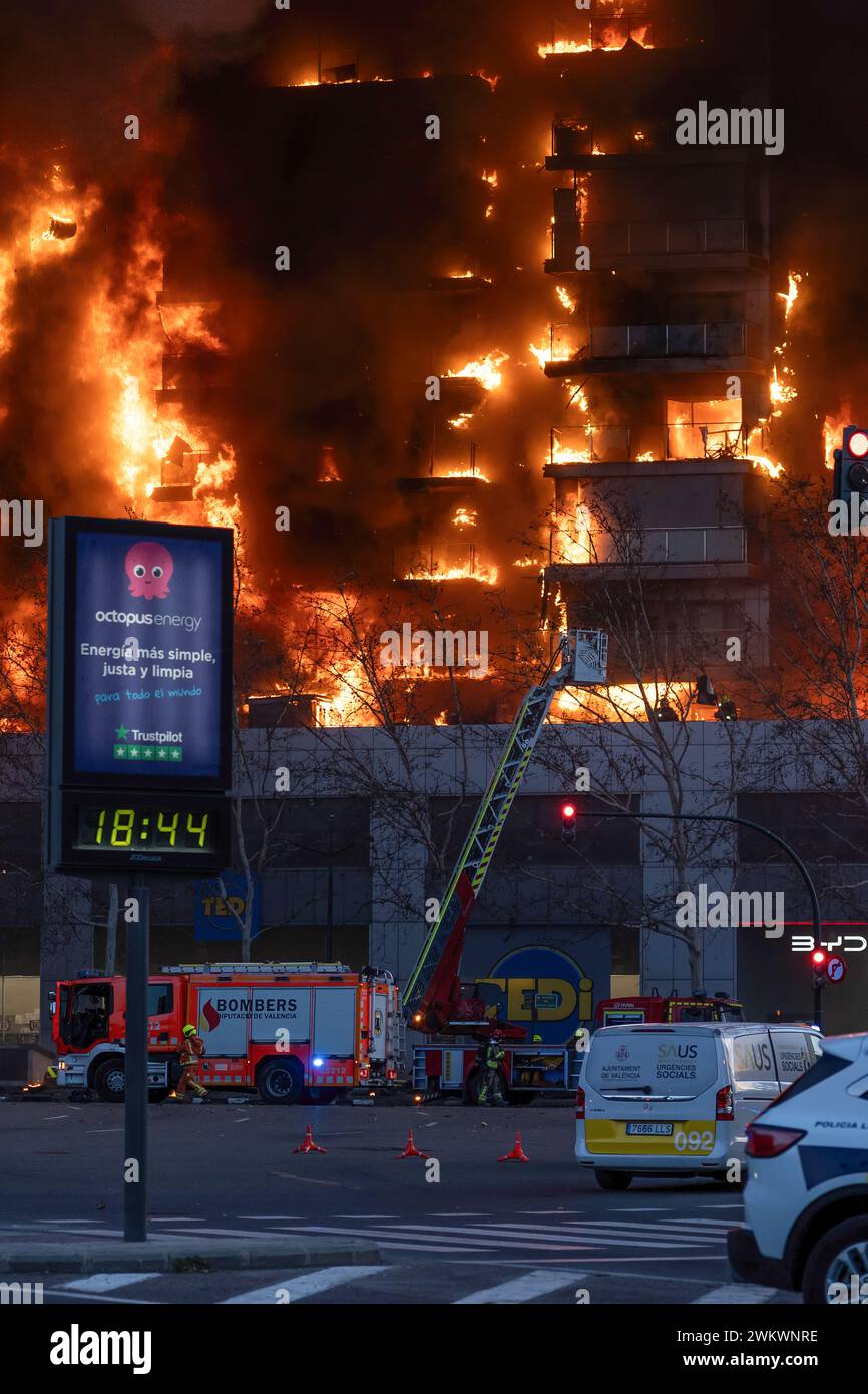 Valence, Espagne - 22 février 2024 : Groupe de pompiers s'échappant d'un grand incendie de bâtiment résidentiel à travers l'échelle du camion dans la ville Banque D'Images
