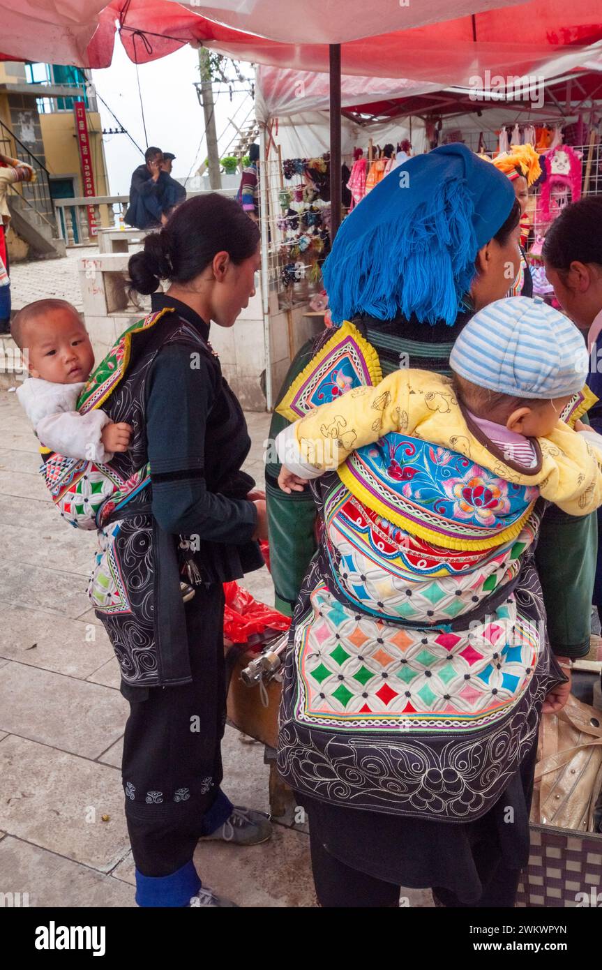 Deux femmes de la minorité ethnique hani avec un porte-bébé sur le dos faisant leurs courses dans un marché local, à Yuanyang, Yunnan, Chine Banque D'Images