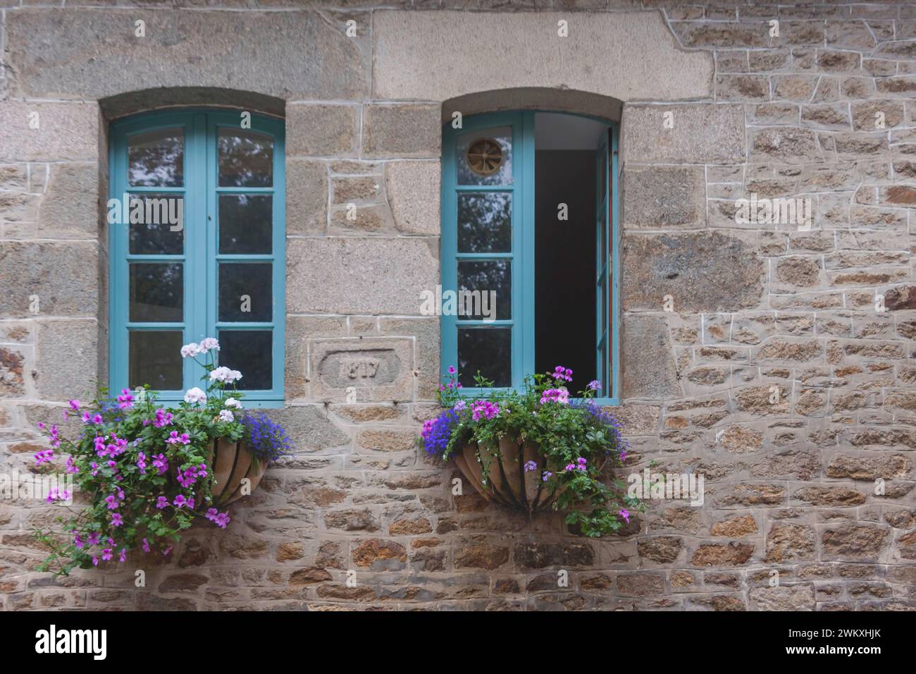 Deux fenêtres dans une maison typique en granit, décoration florale, vieille ville de Dinan, Bretagne, France Banque D'Images